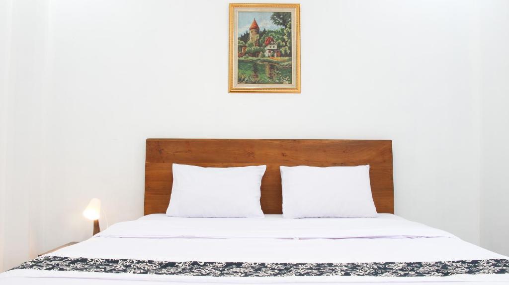 a bed with white sheets and a picture on the wall at Donna's Hus in Demangan