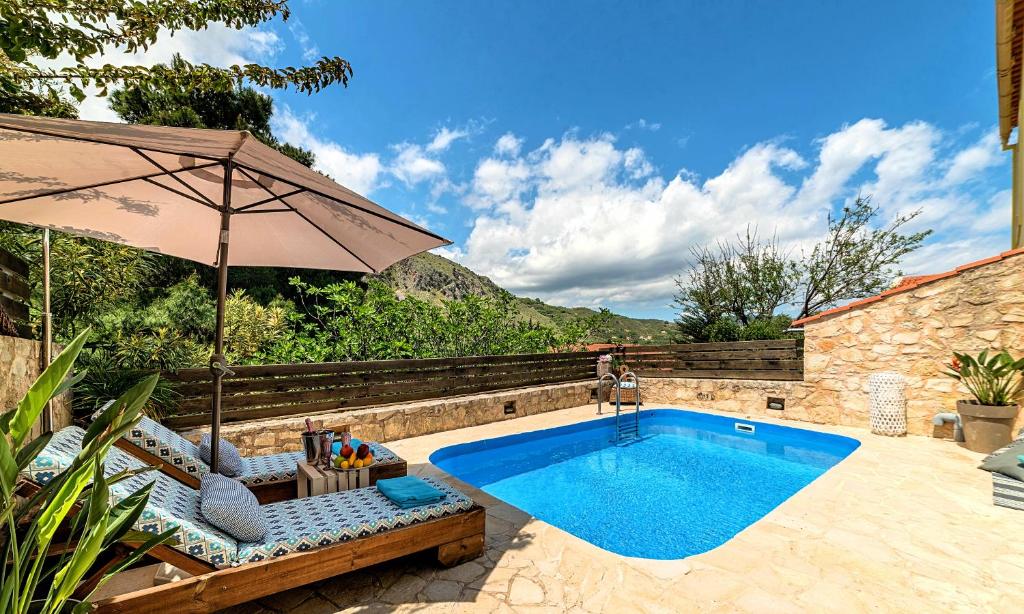a swimming pool with an umbrella and chairs next to a pool at Apple Villas in Mouríon