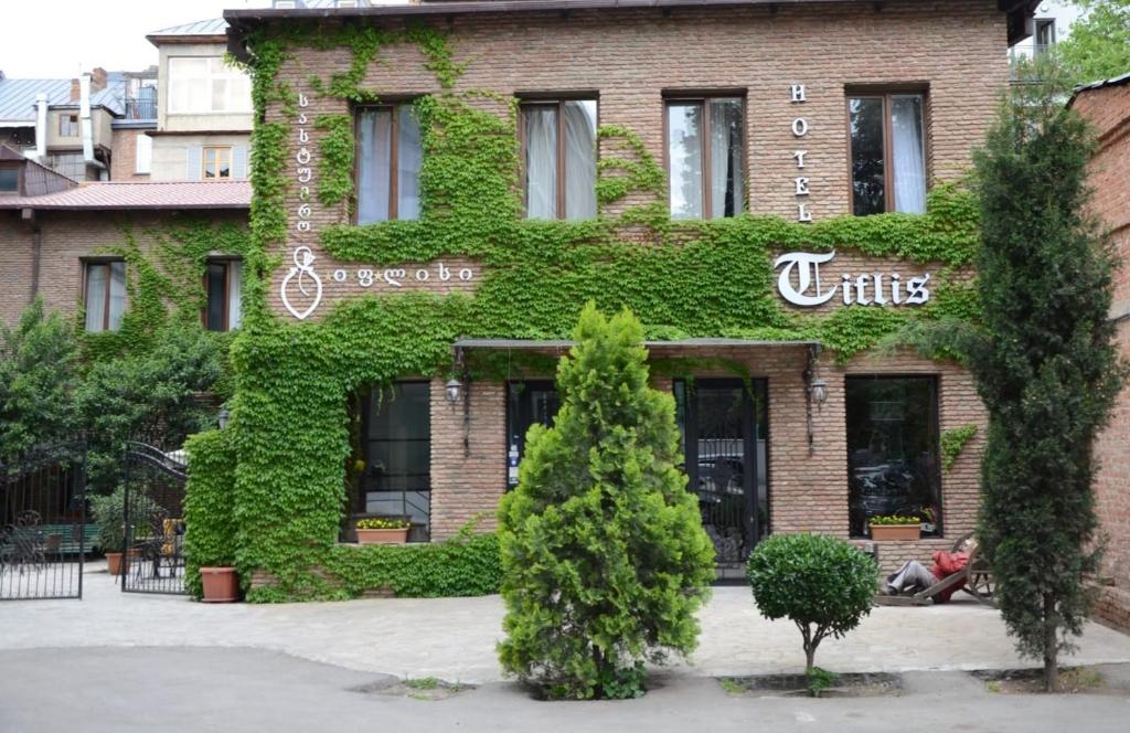 a building covered in ivy with a man sitting in front at Tiflis Hotel in Tbilisi City