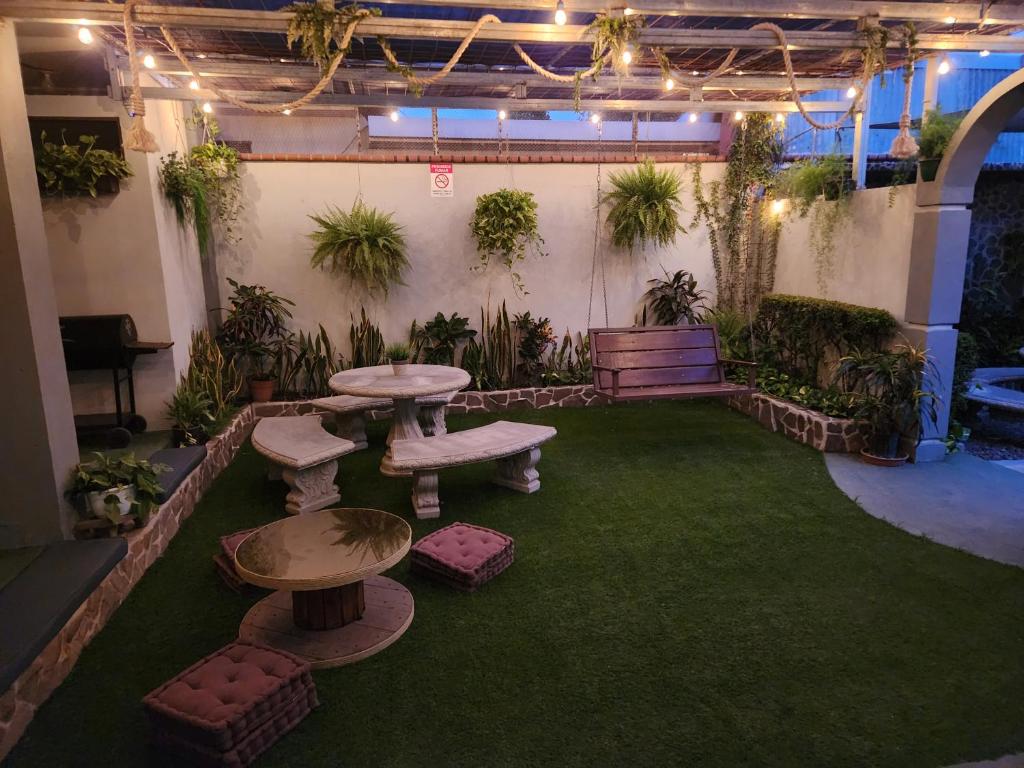 a patio with tables and benches and plants at Hostel El Pretal in Liberia