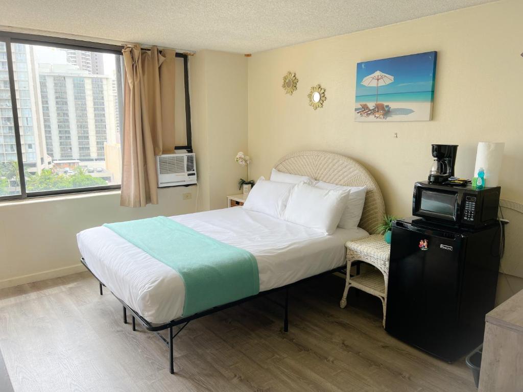 Schlafzimmer mit einem Bett, einem TV und einem Fenster in der Unterkunft Hawaiian Monarch 1105 condo in Honolulu