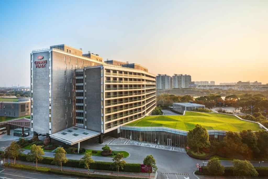 Crowne Plaza Shanghai Xiayang Lake, an IHG Hotel في Qingpu: مبنى كبير بسقف أخضر في مدينة