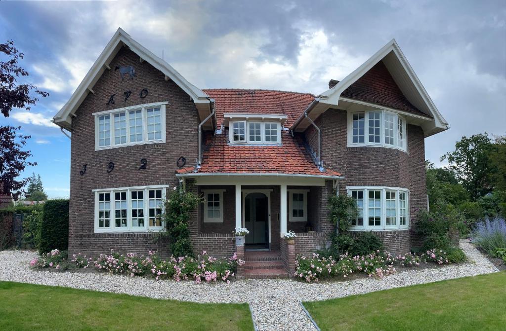 een groot bakstenen huis met bloemen in de voortuin bij Bed and Breakfast Goes in Goes