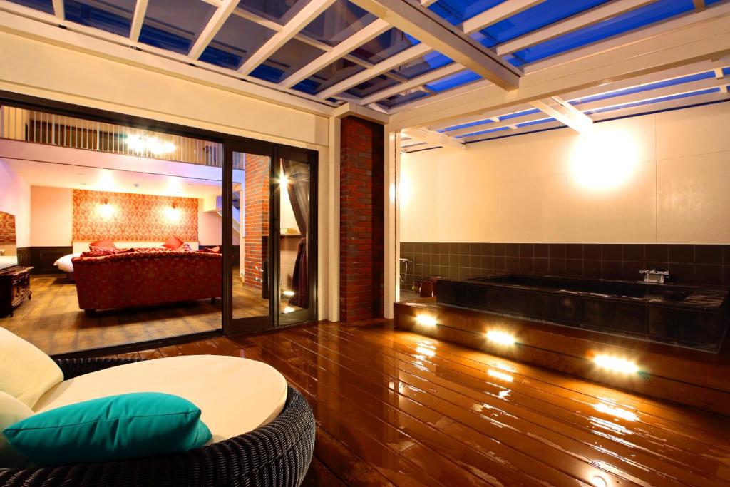 リバティーリゾート大東温泉 في كاكِغو: غرفة معيشة مع أريكة وحوض استحمام