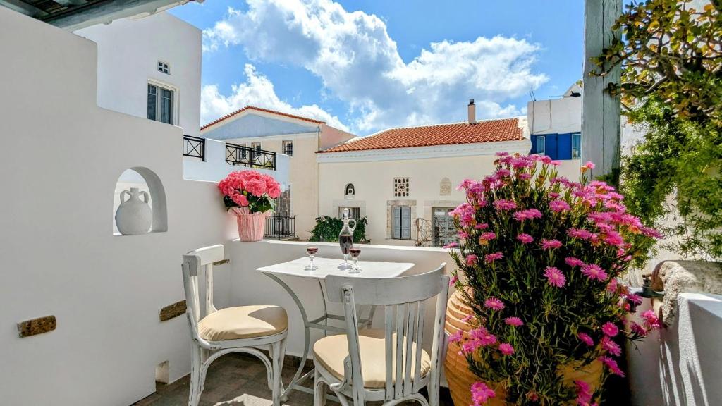balkon ze stołem, krzesłami i kwiatami w obiekcie Anoi Rooms w mieście Tinos