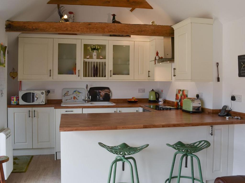 a kitchen with white cabinets and wooden counter tops at The Olde Barn in Dunholme