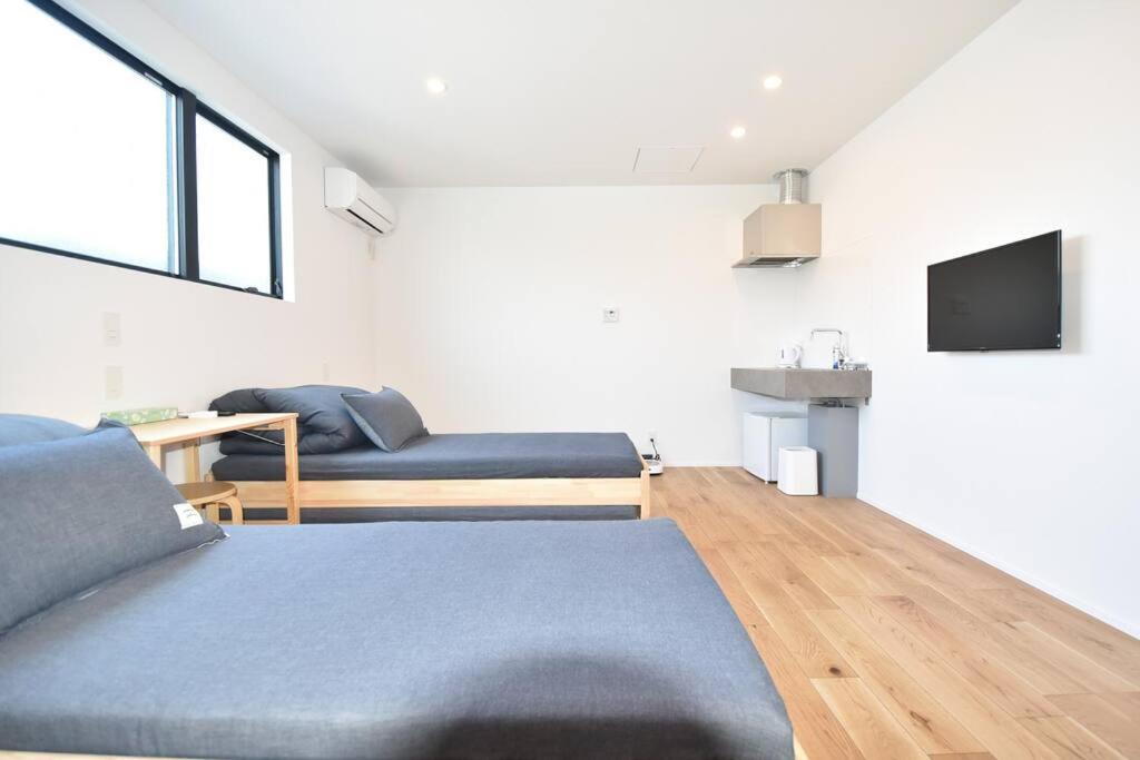 a living room with two beds and a tv at Enzo Ikeda A in Omura