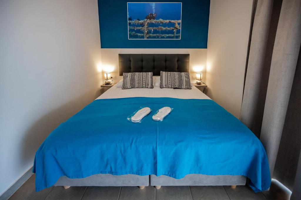 a bedroom with a blue bed with two slippers on it at Premantura Resort - Hotel & Restaurant in Premantura