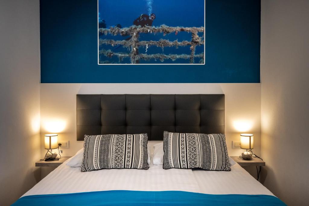 a bed with two pillows and a blue painting above it at Premantura Resort - Hotel & Restaurant in Premantura