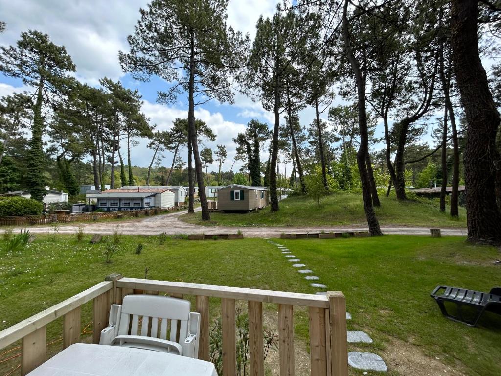 a deck with a table and chairs in a yard at LE ILÔ - camping la dune blanche in Camiers