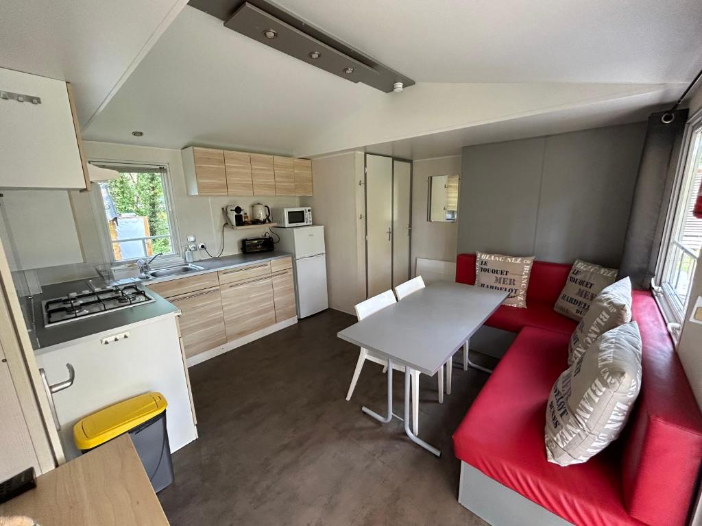 a kitchen and a living room with a red couch and a table at LE ILÔ - camping la dune blanche in Camiers