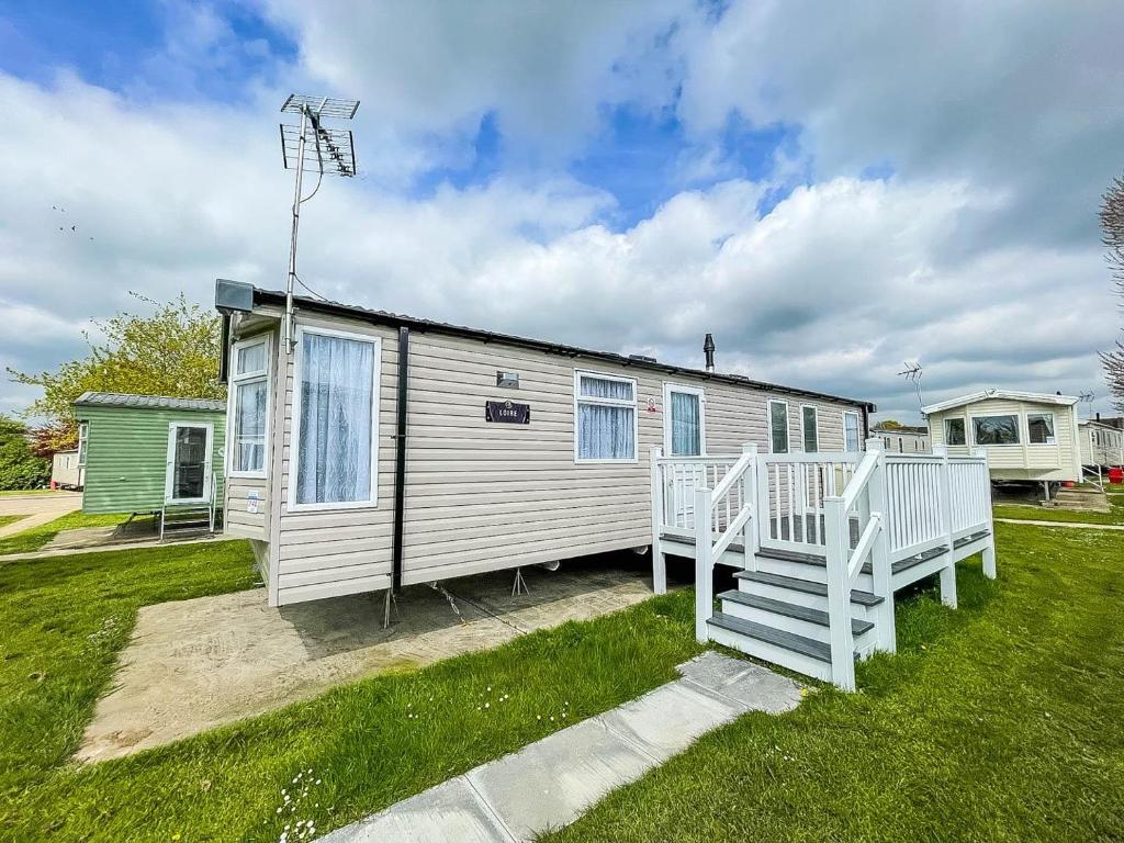 een stacaravan met een veranda en een huis bij Beautiful Caravan With Decking And Free Wifi At Highfield Grange Ref 26740wr in Clacton-on-Sea