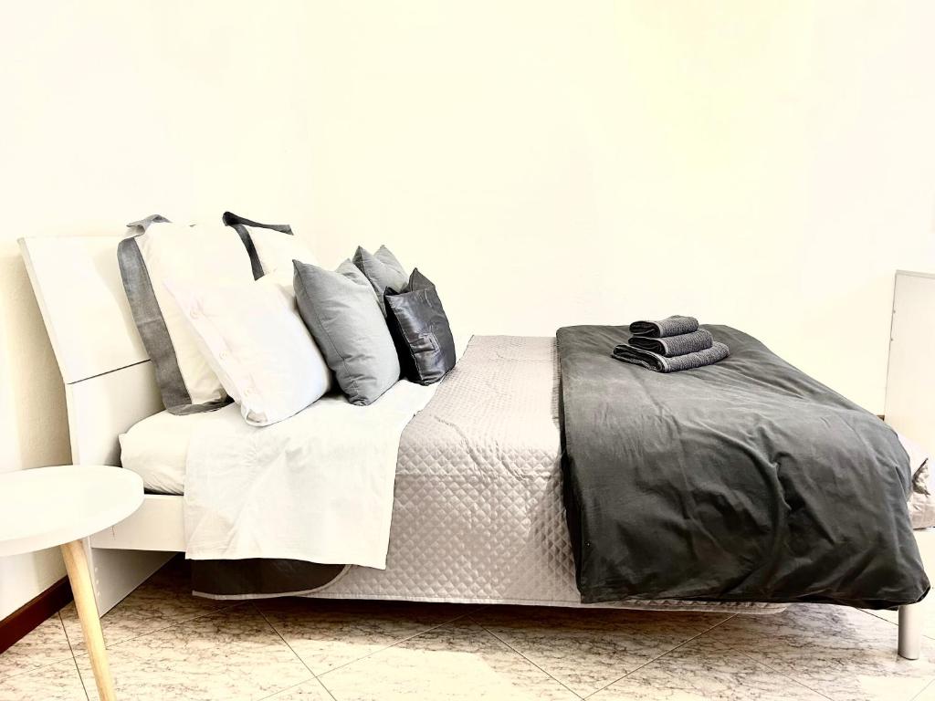 a bed with black and white sheets and pillows at SM Hospitality LAGHI in Reggio Emilia