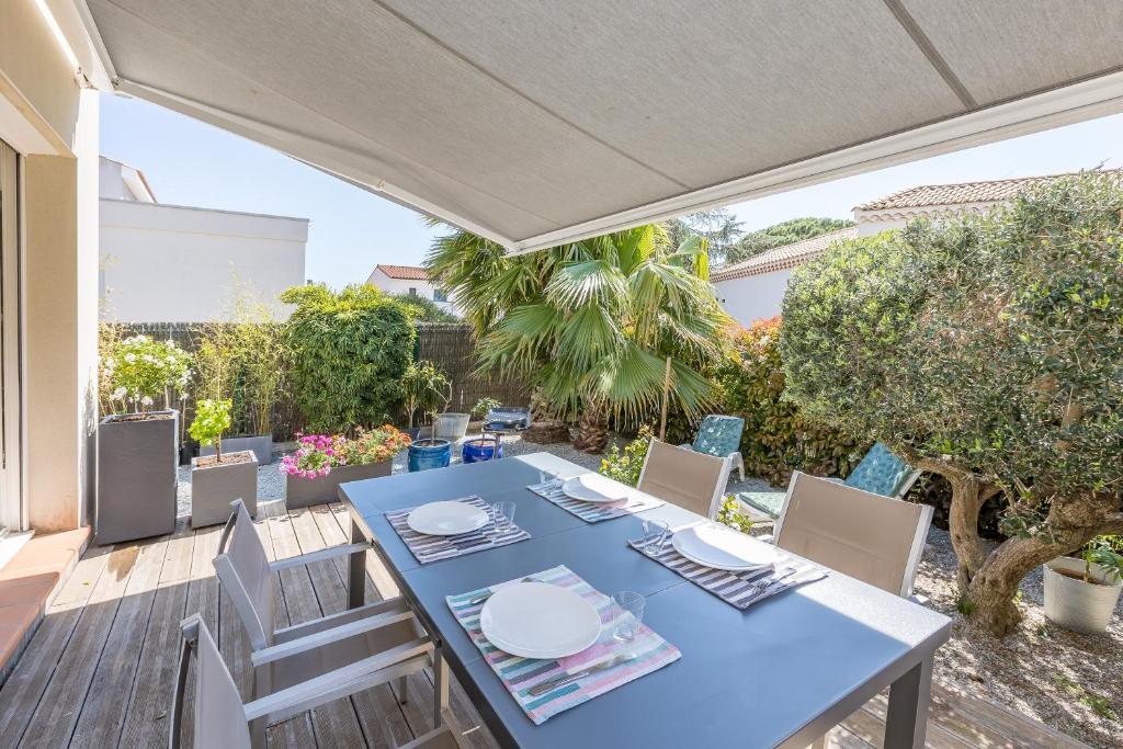 Une table à manger bleue et des chaises sont disponibles sur la terrasse. dans l'établissement Cibelle - Charmante maison avec terrasse, à Cers
