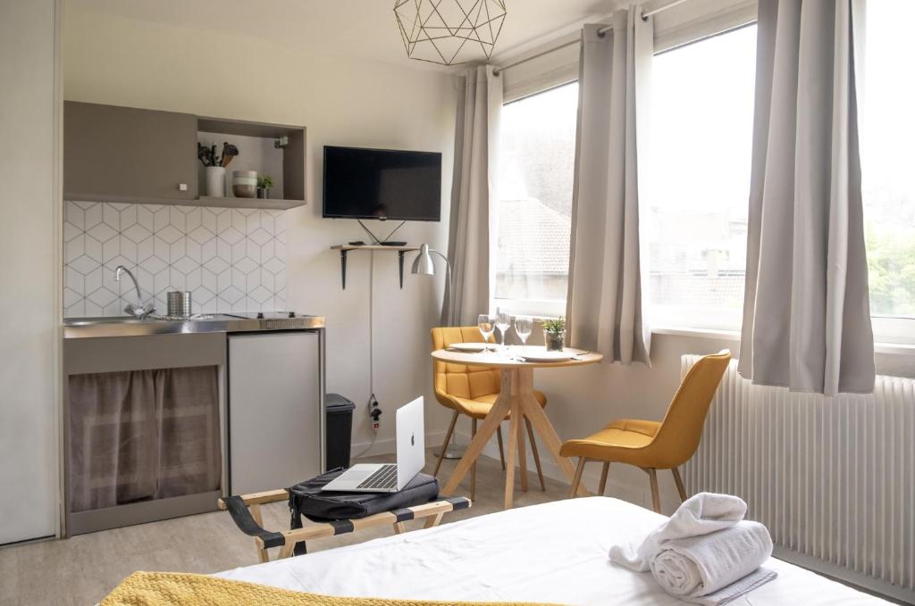 a bedroom with a bed and a table and a kitchen at Le Petit Vauban in Strasbourg