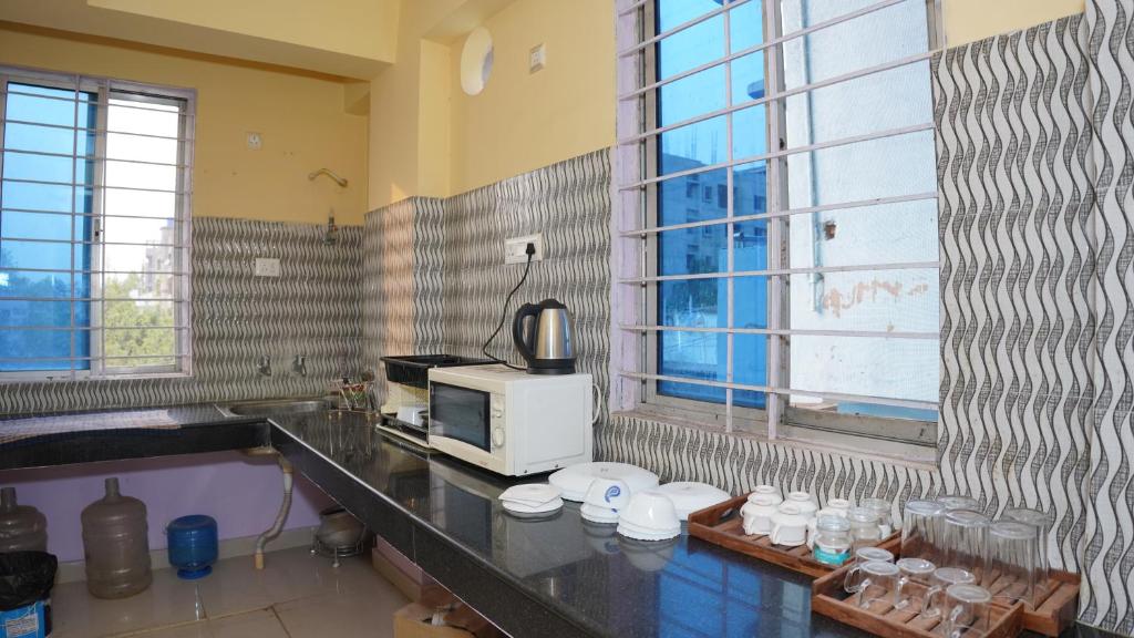 a kitchen with a microwave and a counter with cups at The Royals Home Stay in Deoghar