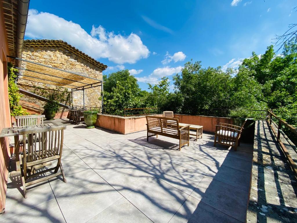 eine Terrasse mit 2 Bänken, einem Tisch und Stühlen in der Unterkunft Beauregard Cévennes - Superbe chambre d'hôtes moderne et indépendante in Monoblet
