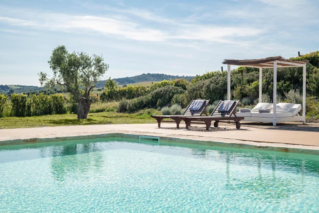 two chairs and a bench next to a swimming pool at Locanda Fontelupa in Campagnatico