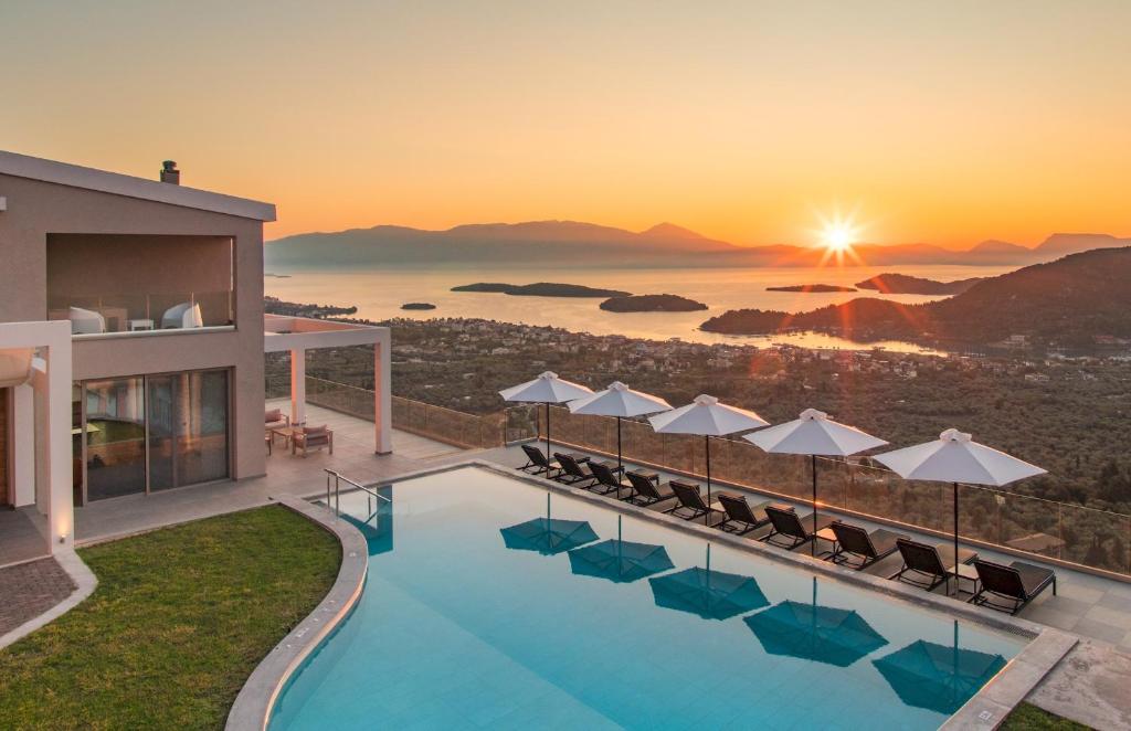 a resort pool with chairs and the sunset in the background at Callista in Palaiokhóri