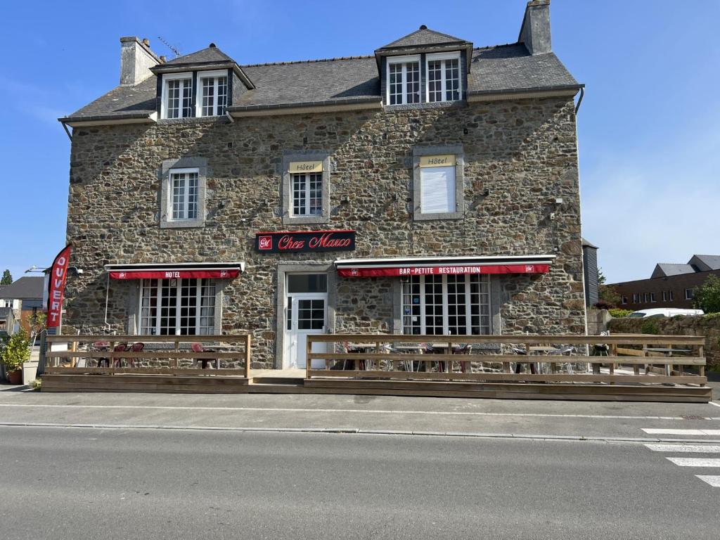 un edificio in pietra con panchine di fronte di Chez Marco a La Gouesnière