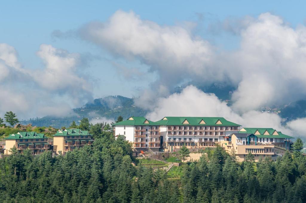 ein Hotel auf einem Hügel mit Bäumen in der Unterkunft Taj Theog Resort & Spa Shimla in Shimla