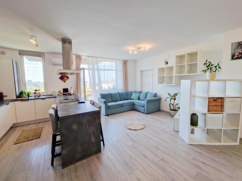 una grande cucina e un soggiorno con divano blu di AZUR Apartment a Timişoara