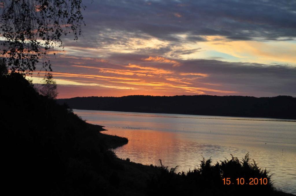 una puesta de sol sobre un gran cuerpo de agua en Norsk Bjlkehus Med Fjordudsigt, en Hobro