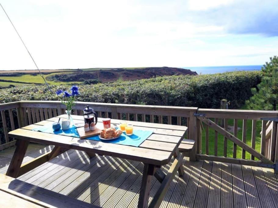 a picnic table on a deck with a view of the ocean at 22 Salcombe Retreat Uninterrupted View to the Sea in Soar