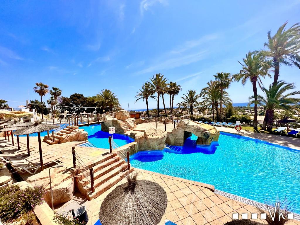 una piscina en un complejo con palmeras en VH Costa Blanca - Apartamento Abantos, en Calpe