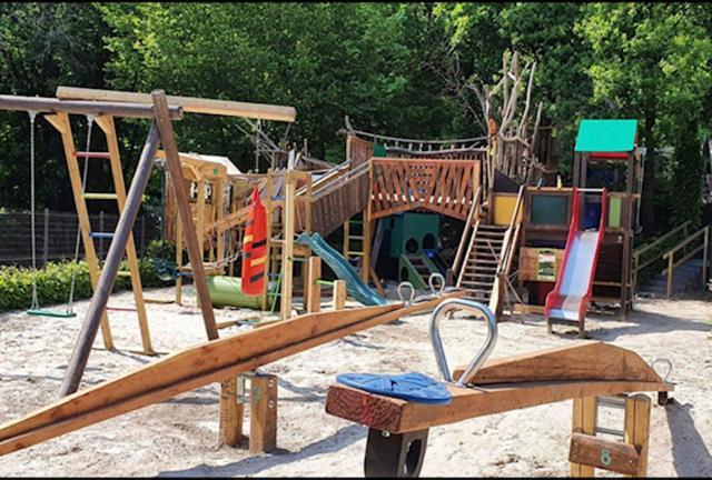 a playground with a wooden swing set in the sand at Chalet Woods in Durbuy