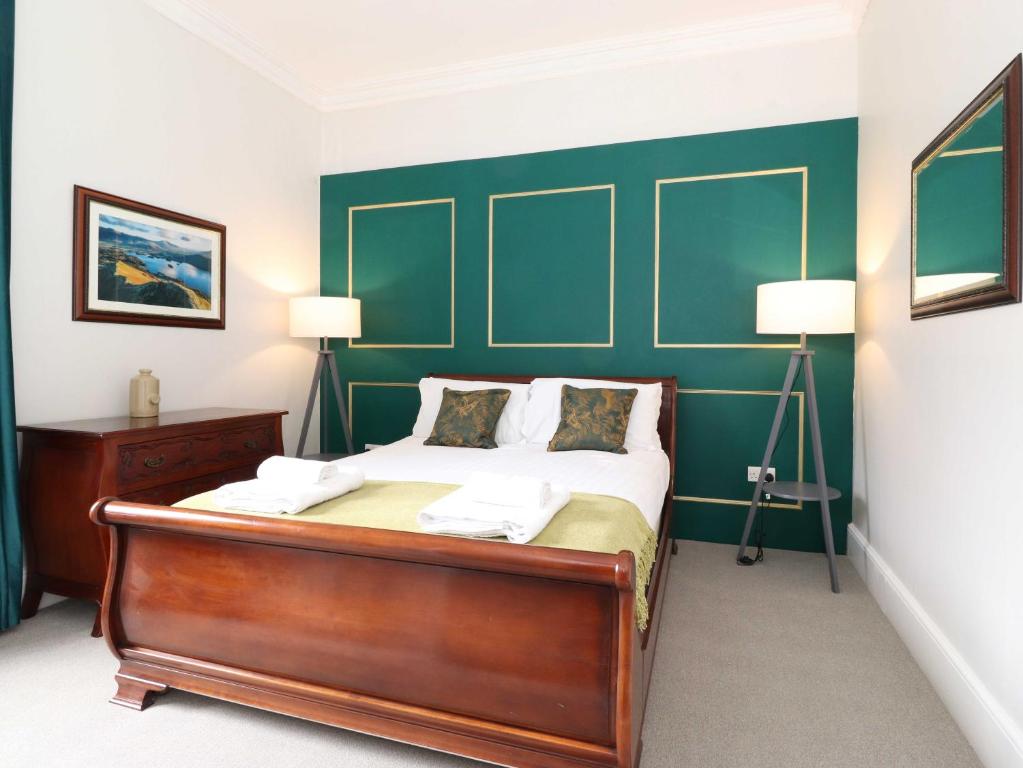 a bedroom with a bed with a green headboard at Cameron Fell Apartment Keswick in Keswick