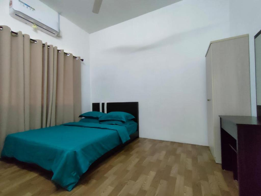 a bedroom with a bed with a blue comforter at Inapan desa bukit papan in Kuala Perlis