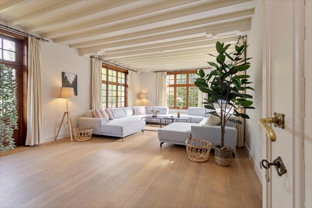 uma sala de estar com sofás brancos e uma mesa em Villa Pauline em De Panne