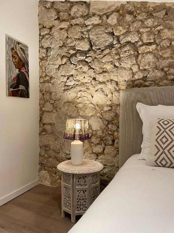 a bedroom with a bed and a table with a lamp at La Maison du Clocher in Saint-Émilion
