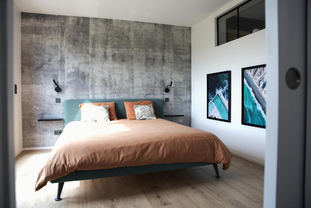 een slaapkamer met een bed en een betonnen muur bij Peaceful Modern 2 BR Penthouse with nice view in Hesperange