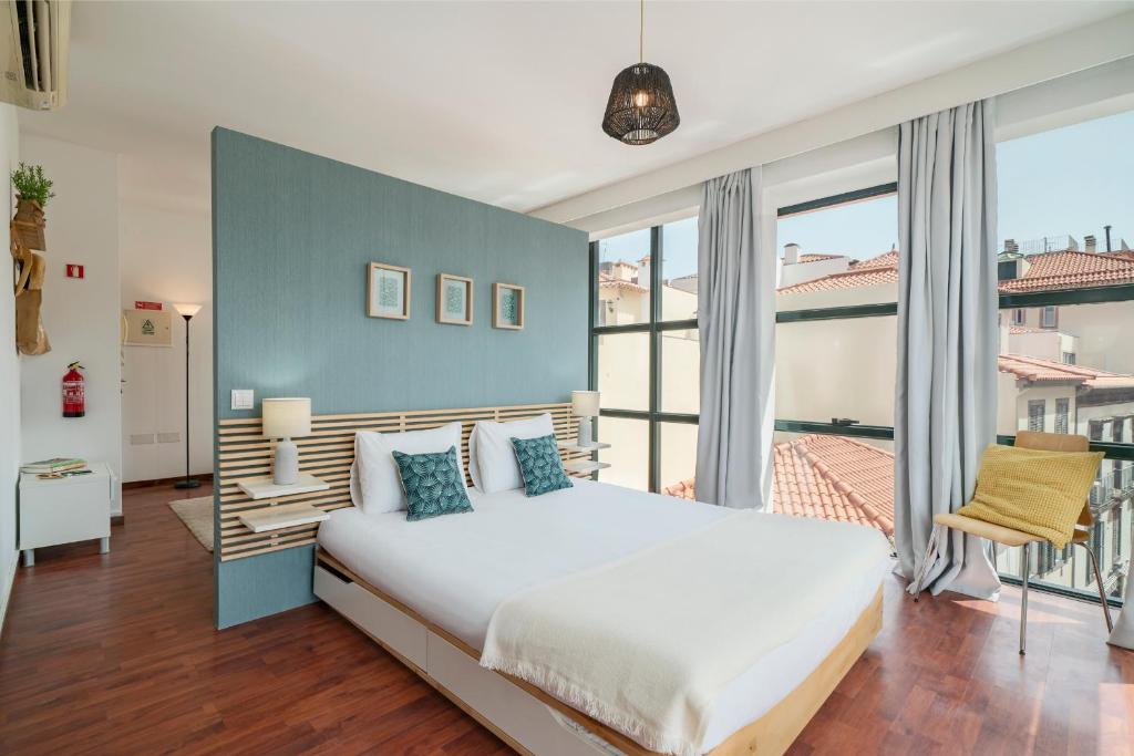 1 dormitorio con 1 cama grande y pared azul en Pelourinho Apartments by An Island Apart, en Funchal