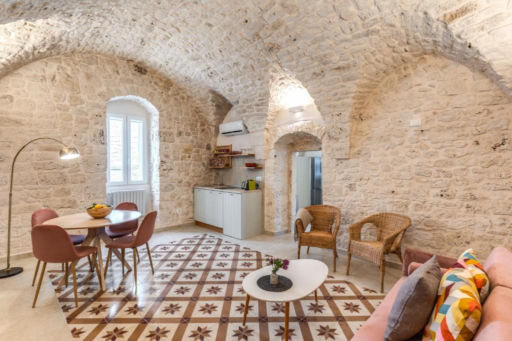 sala de estar con paredes de piedra, mesa y sillas en Il Violino e Il Sassofono, en Ceglie Messapica