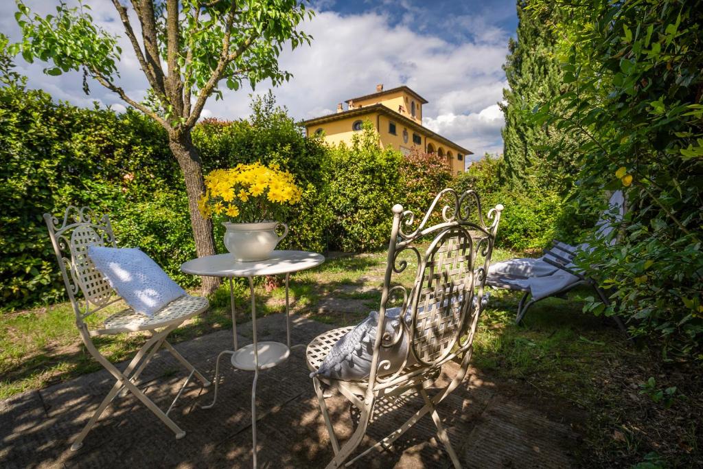 een tafel en stoelen in een tuin met een gebouw bij La Colombaia in Massa e Cozzile