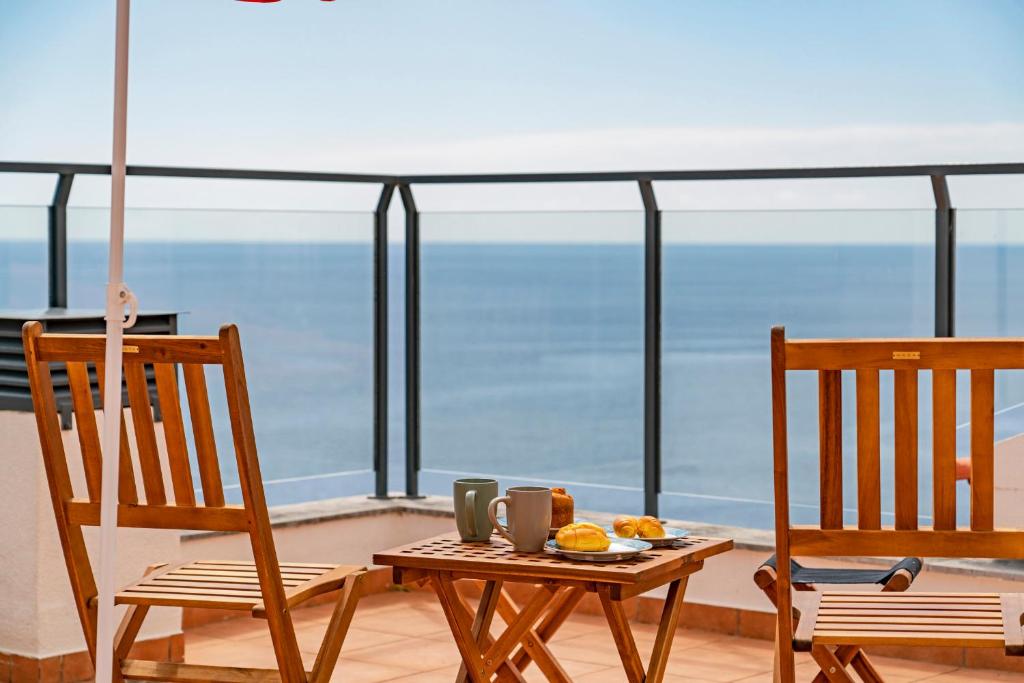 Apartamento Lobo Marinho by An Island Apart في سانتا كروز: طاولة وكراسي على شرفة مطلة على المحيط