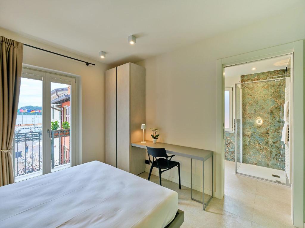 a bedroom with a bed and a desk and a window at Piccolo Hotel in Garda