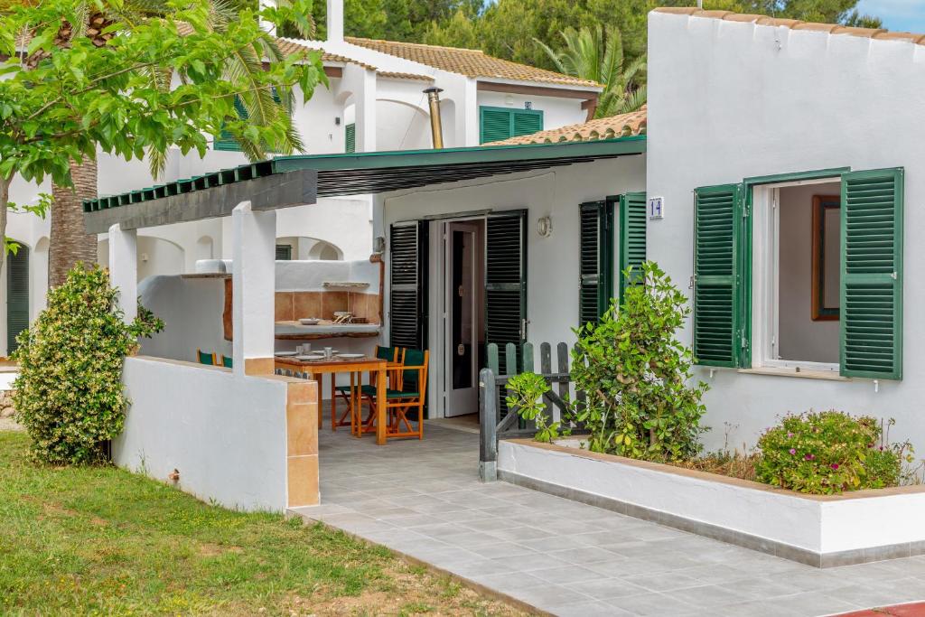 a white house with green shutters and a patio at Son Xoriguer 14 in Son Xoriguer