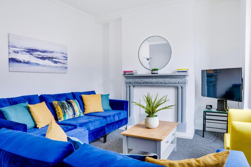 Spacious 4 Bedroom house near Leeds CC في Beeston Hill: غرفة معيشة مع أرائك زرقاء ومرآة
