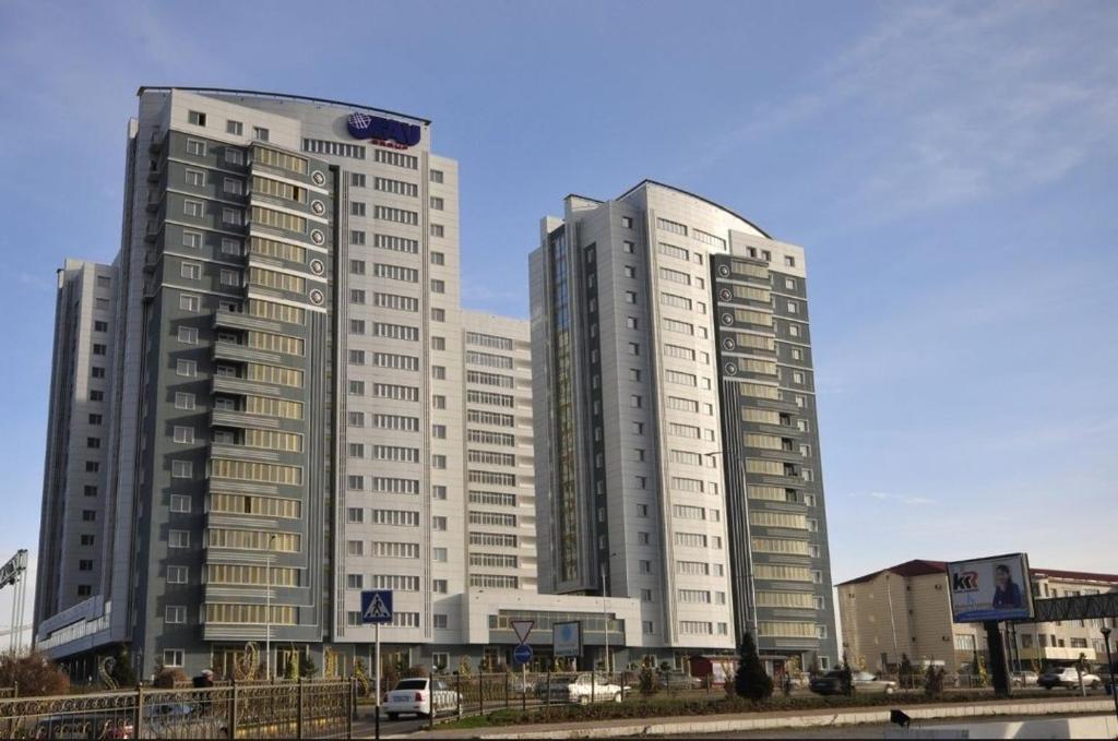 dois altos edifícios brancos numa cidade em Апартаменты в жилом комплексе БИИК em Shymkent