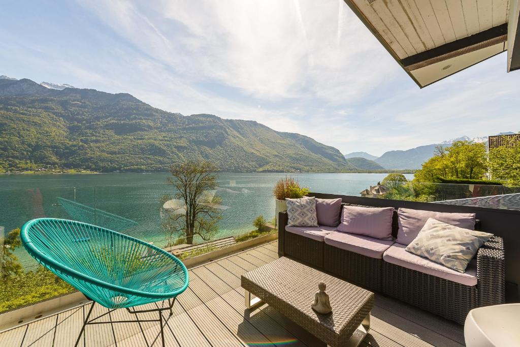 a patio with a couch and a chair and a view of a lake at Les Eaux Cristallines de Bredannaz, unique vue lac 6p LLA Selections by Location lac Annecy in Doussard