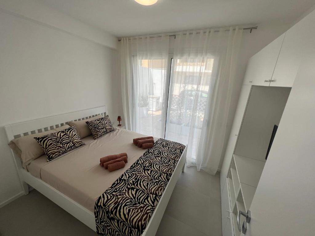 a white bedroom with a large bed with brown pillows at Windsurf Beach Front in Torre Grande