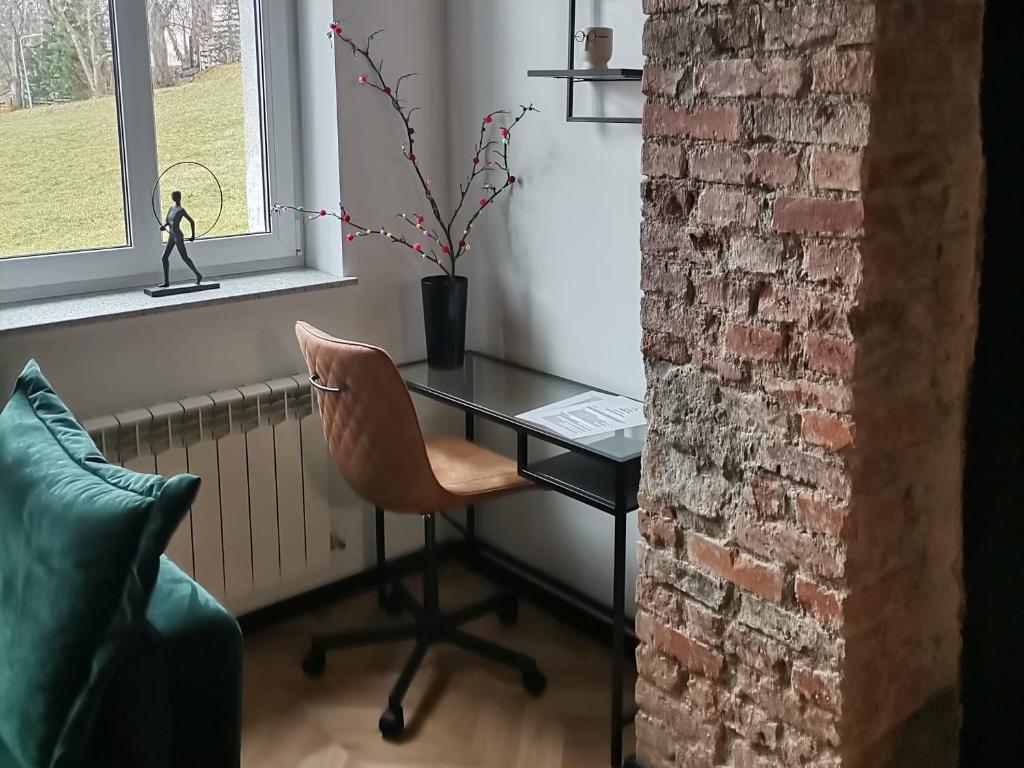 a desk and a chair in a room with a brick wall at Apartament Gór-Ski Saneczkowa in Karpacz