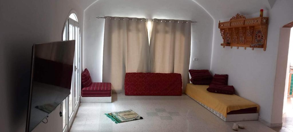 a living room with a tv and red chairs at Renaissance in Bou Ficha