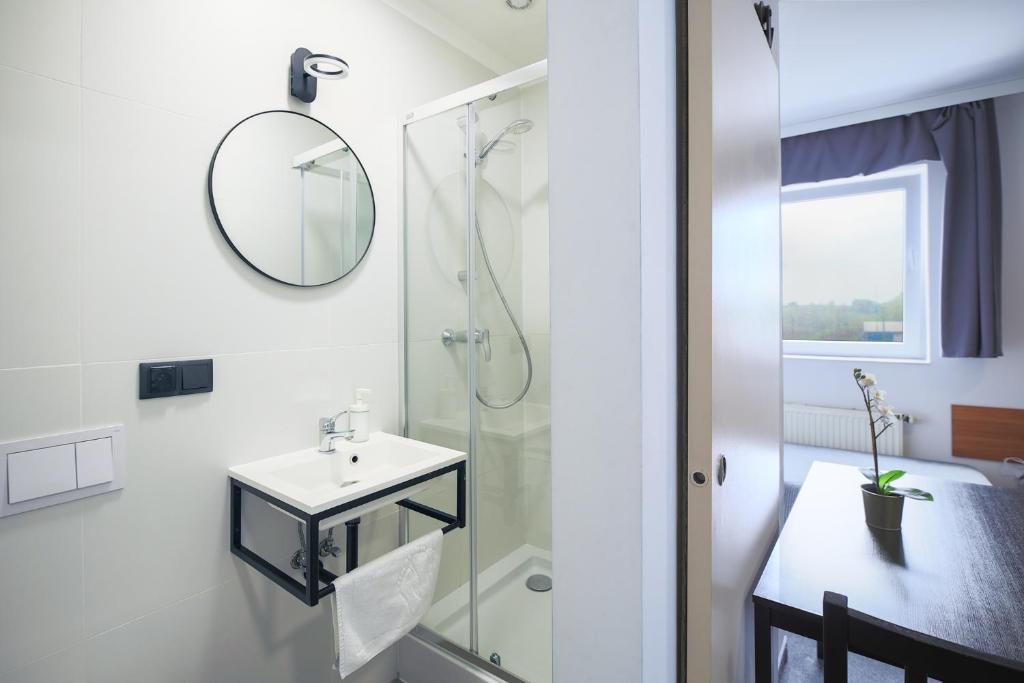 ein Bad mit einer Dusche, einem Waschbecken und einem Spiegel in der Unterkunft Hotel pod Wieliczką in Gdów