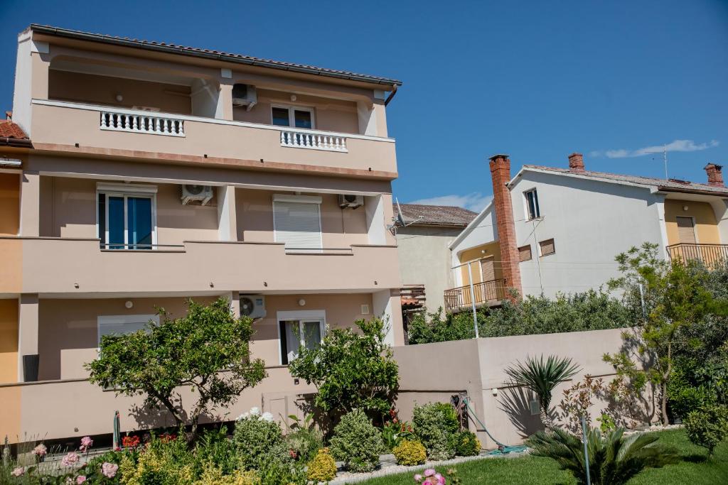 an apartment building with trees and bushes at Apartments Luka in Rab