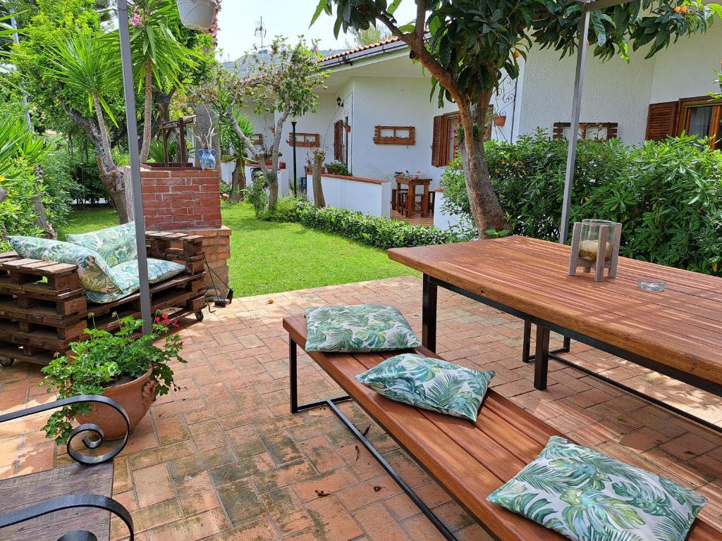 un patio con una mesa de madera y un banco en Litto Appartamenti, en Tropea